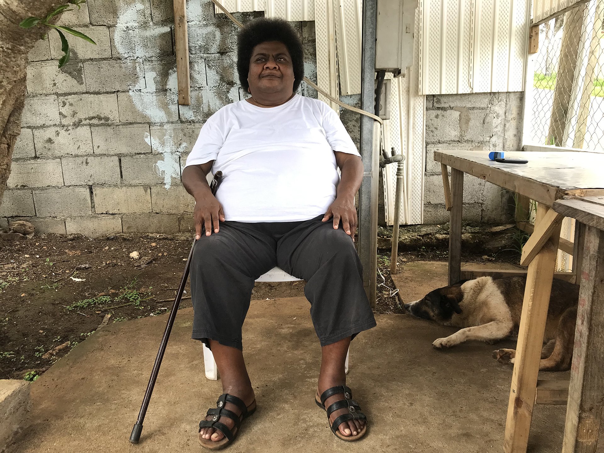 person sitting on a chair holding a walking stick
